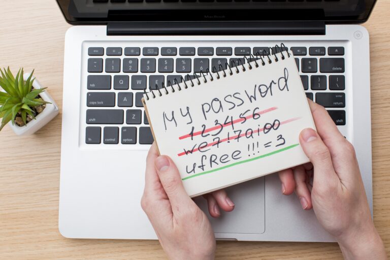 flat-lay-hands-holding-notebook-with-password-laptop